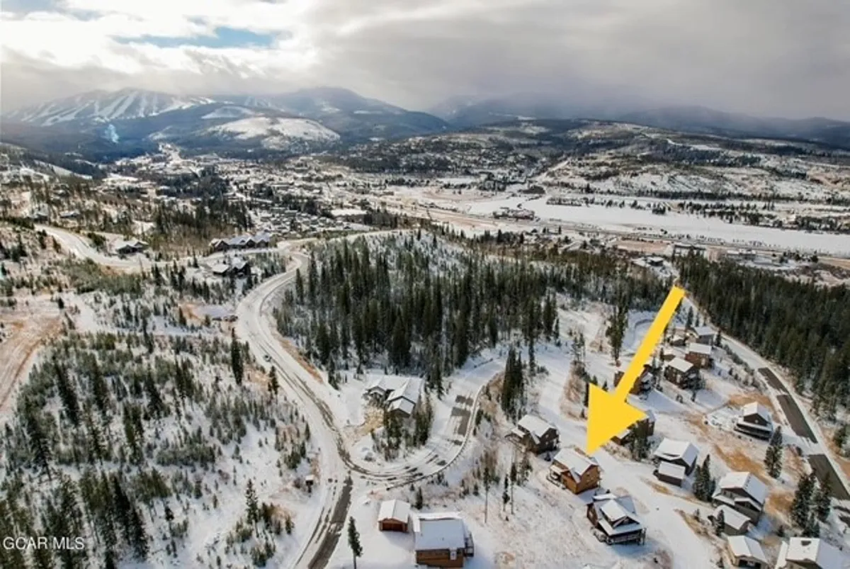 This image captures a serene snow-covered landscape with winding roads, surrounding mountains, and scattered houses. The peaceful outdoor setting showcases the beauty of the mountain environment that guests and their pets can enjoy together.