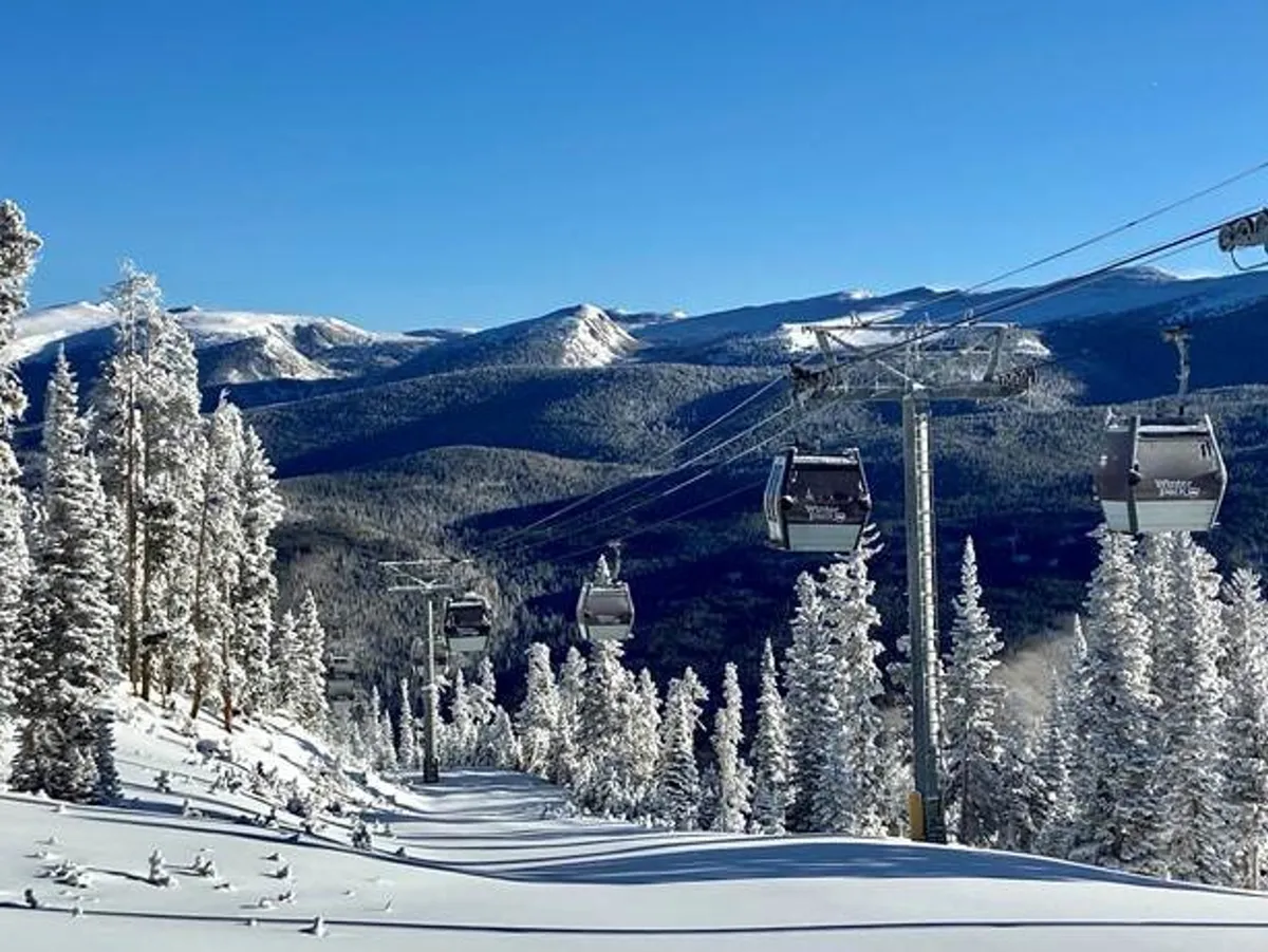 A dramatic exterior scene with a ski lift gliding above snow-covered mountains and pine trees. The shot captures the thrill of winter sports and the expansive natural beauty surrounding the villa, inviting viewers to imagine themselves riding up for a day on the slopes.
