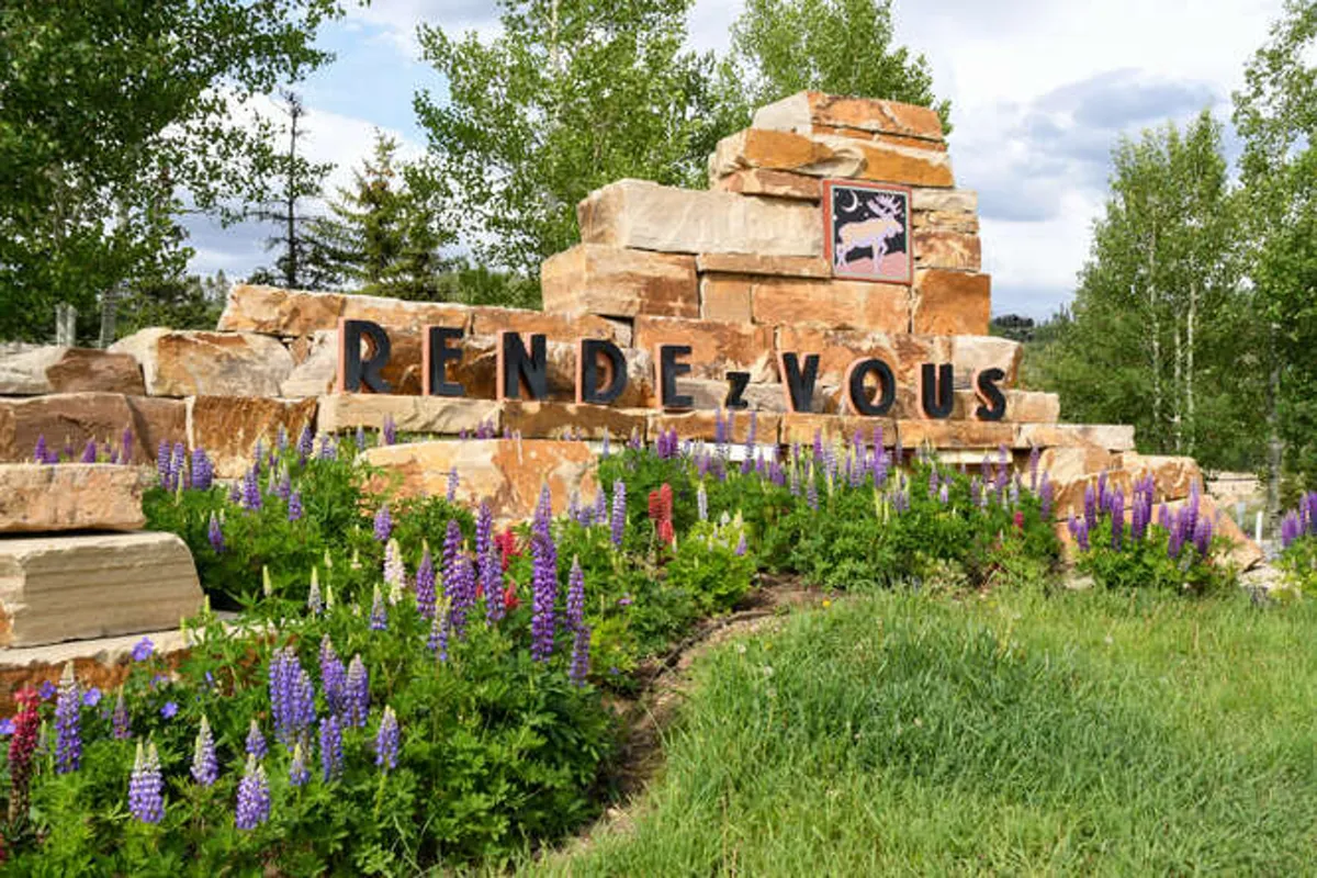 This image displays the exterior of the property, featuring a prominent stone sign surrounded by lush flower beds and mature trees. The scene conveys a sense of arrival, privacy, and tranquility, inviting guests to experience the villa's serene setting.