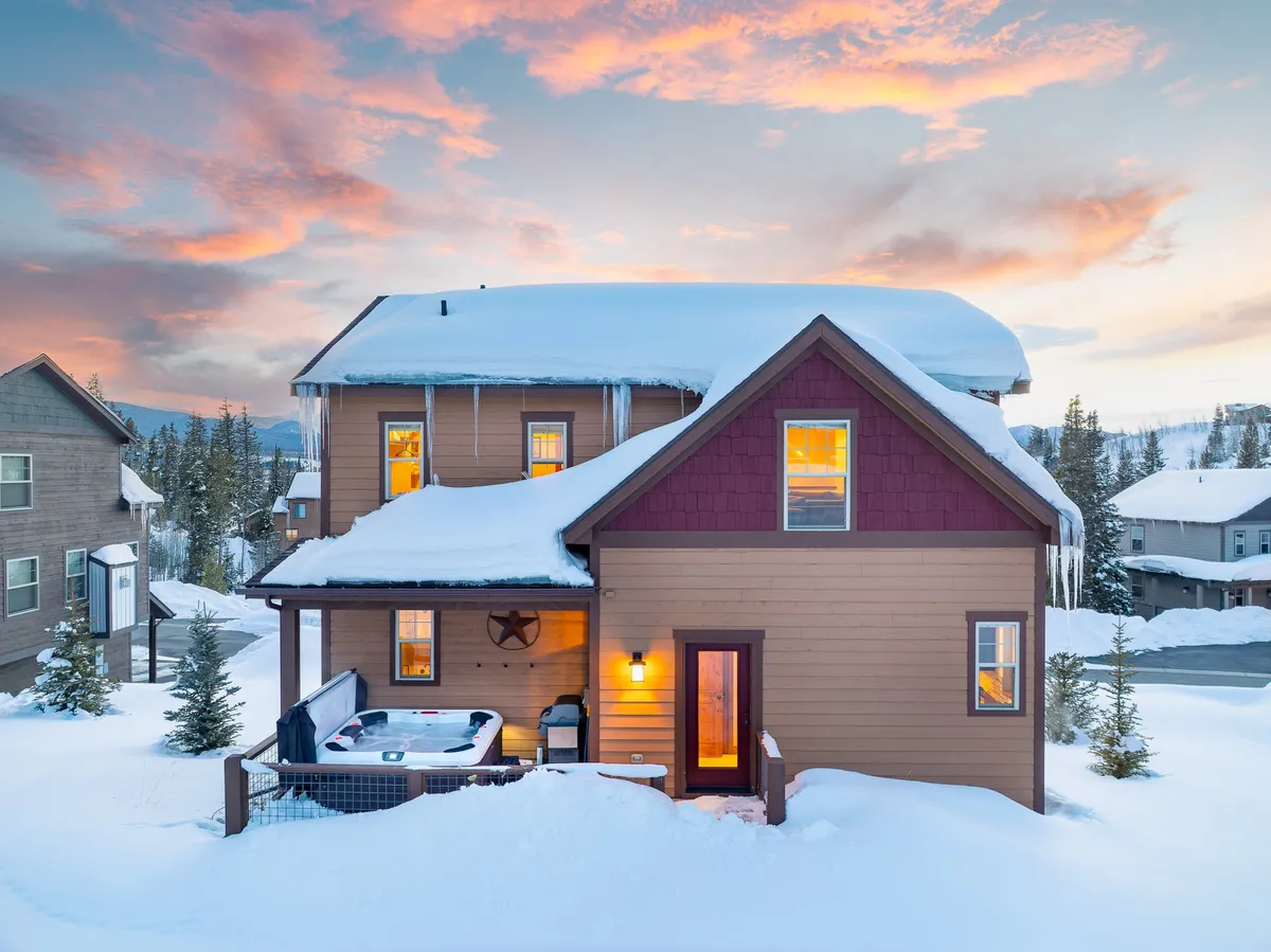 An inviting exterior shot of the villa’s hot tub glowing warmly amid a snowy landscape, with illuminated windows promising cozy comfort inside. The scene suggests relaxation and recovery after a day of outdoor exploits, with the juxtaposition of cold snow and steamy hot tub creating a compelling sense of reward and renewal.